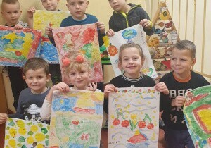 Dzieci stoją wszystkie razem. Uśmiechają się do zdjęcia. Trzymają w rękach prace plastyczne dotyczące czystości.