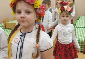 Dziewczynki ubrane odświętnie. Na głowach maja wianki.