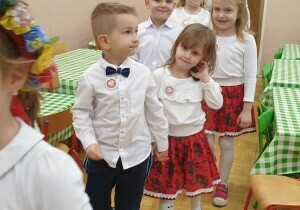 Dziewczynka z chłopcem stoi w parze. Ubrani są odświętnie.