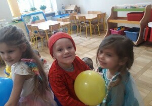 Chłopiec z dziewczynką tańczą z balonem.