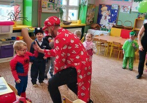 Nauczyciel przebrany za klauna wita się z chłopcem. Chłopiec przebrany jest za spidermana.