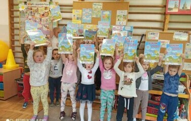 Dzieci stoją w sali przedszkolnej. Uśmiechają się do zdjęcia. W rękach trzymają dyplomy z kulturą mi do twarzy.