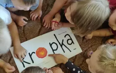 Dzieci oglądają ksiązkę pod tytułem "Kropka"