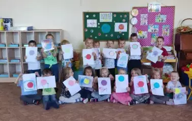 Zdjęcie grupowe. Dzieci stoją. Trzymają w rękach kartki z narysowanymi kropkami.