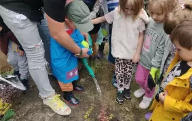 Nauczyciel podlewa z dzieckiem rośliny.