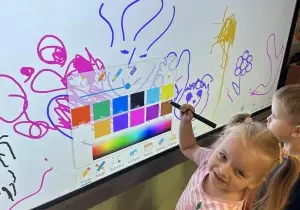 Dziewczynka rysuje na monitorze interaktywnym.
