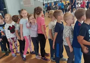Dzieci stoją na sali gimnastycznej jeden za drugim.