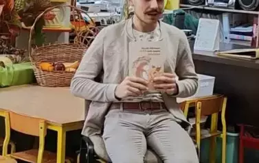 Pan Adam siedzi na krzesełku. W rękach trzyma książkę. Przed nim siedzą dzieci .