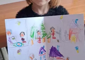 Dziewczynka trzyma w ręku nagrodę, książkę. Uśmiecha się do zdjęcia.
