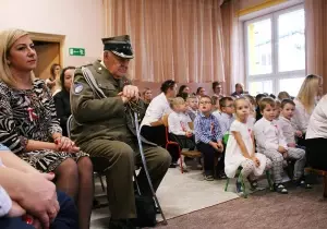 Nauczycielka, kombatant i dzieci siedzą na widowni. Oglądają przedstawienie.