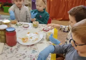 Dzieci wkładają kapustę do słoiczk&oacute;w.