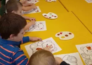 Dzieci malują farbami misia.