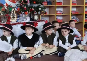 Chłopcy siedzą na dywanie w sali przedszkolnej. Przebrani są za pasterzy.