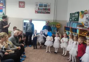 Dzieci ubrane w biale sp&oacute;dniczki występują z okazji dnia babci i dziadka.