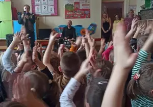 Pan gra na perkusji. Dzieci trzymają ręce w g&oacute;rze i klaszczą.