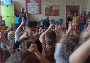 Pan gra na perkusji. Dzieci trzymają ręce w g&oacute;rze i klaszczą.
