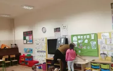 Nauczyciel pomaga dziecku podczas zadania przy tablicy.