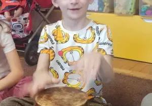 Chłopiec siedzi na dywanie. Gra na bębnie.