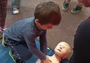 Chłopiec wykonuje resuscytacje na manekinie.