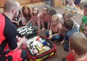 Ratownik pokazuje dzieciom walizkę ratownika.