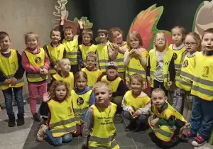 Dzieci stoją w planetraium. Uśmiechają się do zdjęcia.
