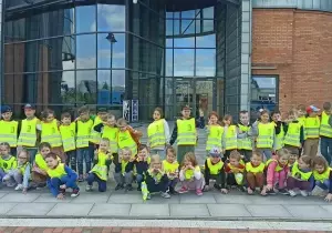 Dzieci stoją w grupie przed planetarium i uśmiechają się do zdjęcia.