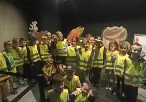 Dzieci stoją w planetraium. Uśmiechają się do zdjęcia.