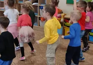Dzieci tańczą w sali przedszkolnej.