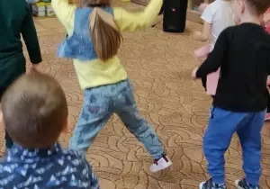 Dzieci tańczą w sali przedszkolnej. Przed nimi stoi pan Bartłomiej instruktor tańca.