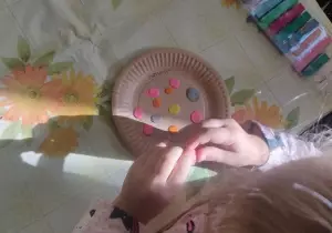 dzieci naklejają kropki z plasteliny na papierowy talerz