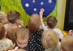 dzieci naklejają małe kropki na dużą kropkę