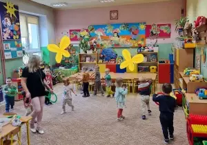 dzieci biegają po sali z kolorowymi k&oacute;łkami