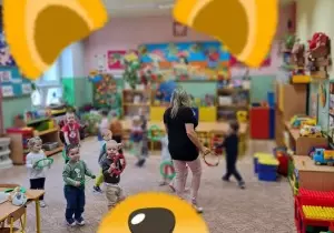dzieci biegają po sali z kolorowymi k&oacute;łkami