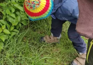Dziecko podnosi śmieci z trawy.