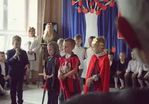 Chłopcy są przebrani za Lecha, Czecha i Rusa. Z boku stoi chłopiec. Ubrany jest w garnitur. Jest narratorem. M&oacute;wi przez mikrofon.