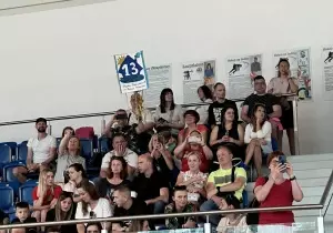 Rodzice siedzą na widowni. Kibicują dzieciom. Robią zdjęcia. Trzymają transparent.