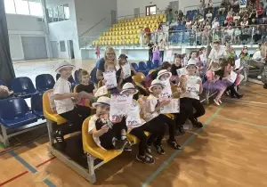 Dzieci siedzą na sali. Czekają na występ. Oglądają występy innych przedszkoli.