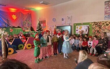 Na scenie stoi siedmiu chłopc&oacute;w przebranych za krasnoludki. Przed nimi dziewczynka dziewczynka przebrana za kr&oacute;lewnę śnieżkę. M&oacute;wi przez mikrofon.