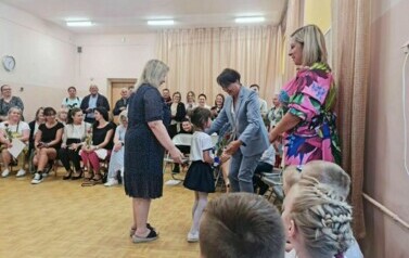 Dziewczynka stoi z kwiatkiem i dziękuje Pani Małgorzacie Andrzejewskiej, zastępcy Naczelnika Wydziału Edukacji i Młodzieży Urzędu Miasta Zgierza.
