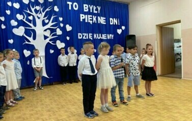 Dzieci stoją na środku sali i m&oacute;wią wiersze.