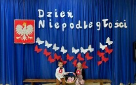 Dzieci siedzą przy dekoracji z okazji Dnia Niepodległości .