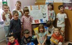 Dzieci stoją przed tablicą dotyczą zbi&oacute;rki karmy do schroniska 