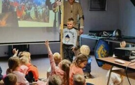 Dzieci siedzą i oglądają film dokumentalny.
