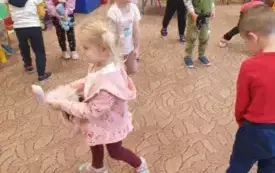 Dzieci chodzą po sali przedszkolnej ze swoimi misiem.