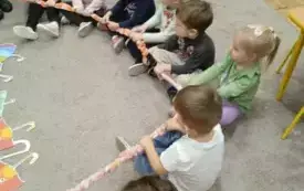 Dzieci siedza na dywanie. W rękach trzymają gumę.