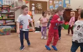 Dzieci chodzą po sali. Razem z nimi nauczycielka.