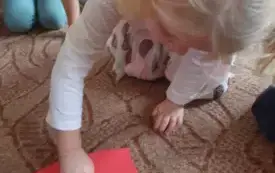 Dziewczynka nachyla się nad serdeuszkiem. Przebija je szpilką.
