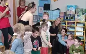 Pani przystawia mikrofon chłopcu. Jest przebrana za kota. Dzieci stoją przed nią. Jeden obok drugiego. 