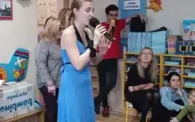 Pani śpiewa przez mikrofon. Ubrana jest w długą niebieską sukienkę.