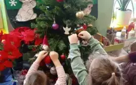 Dzieci wieszają bombki na choince.